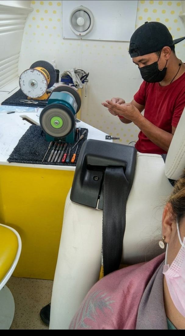 Technician finishing salon scissors while the client watches